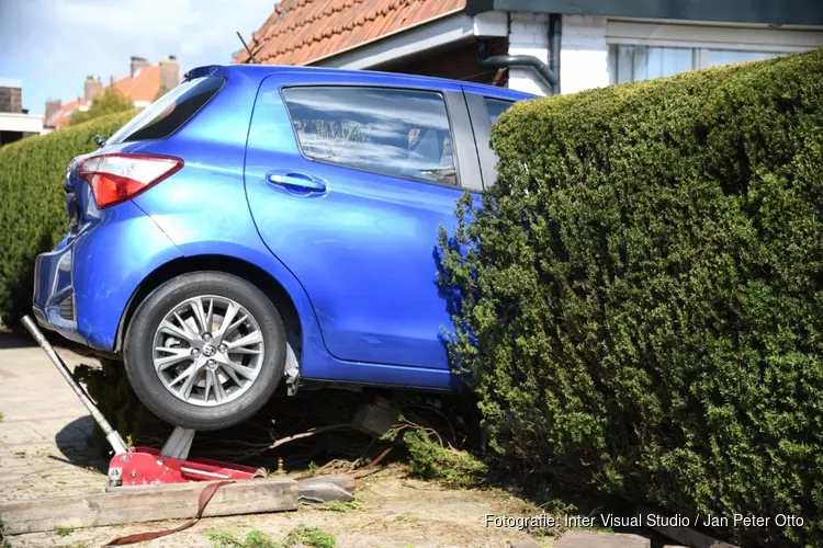 Automobilist rijdt per ongeluk achteruit en komt met voertuig vast in heg te zitten