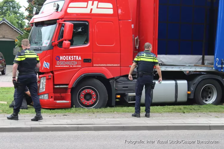 Vrachtwagen rijdt zich vast in het gras in Huizen