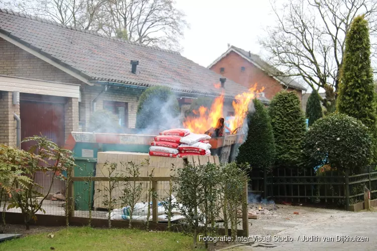 Grote bouwcontainer tegen woning in vlammen opgegaan